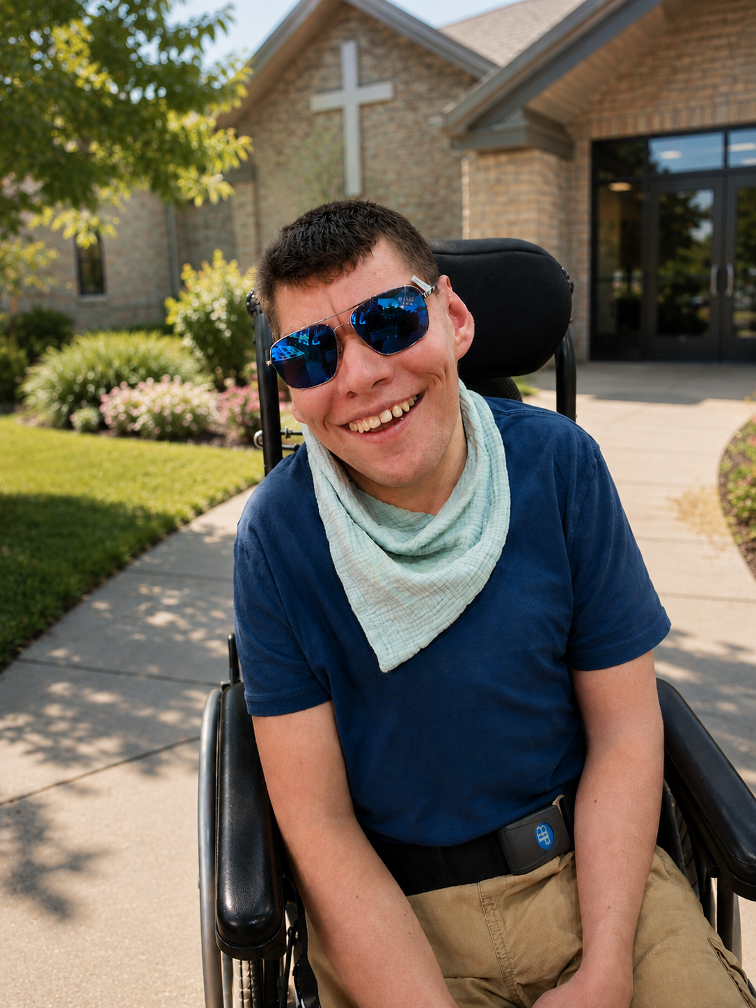 David smiling in his wheelchair outside a church, with a white cross on the building behind him